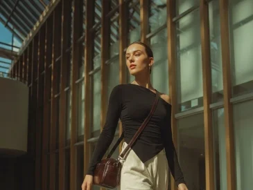 Woman walking in modern building wearing black top and cream trousers